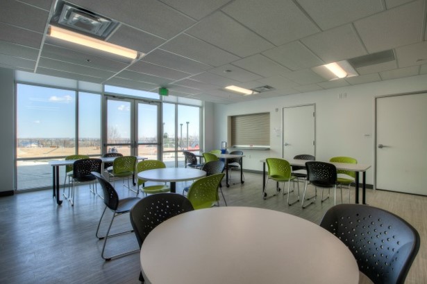 A common area at the Redtail Ponds property features four separate table and chair seating areas with a large floor to ceiling window on the far wall.