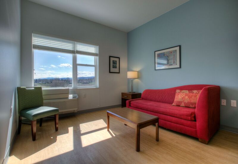 An interior shot of a Redtail Ponds unit. A red couch is against the right wall with a large window looking out over the mountains to the west