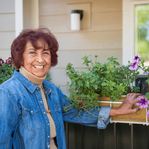 Woman on porch next to purple flowers