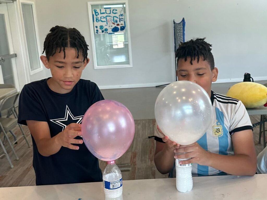 two boys doing a science experiment with balloons